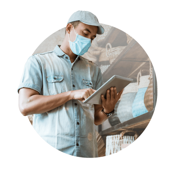 Man with a hat and face mask looking at a tablet
